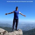 The person standing open-armed on mountain peak